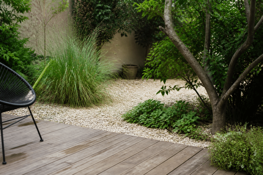 Jardin avec plantes vertes, graviers et terrasse bois