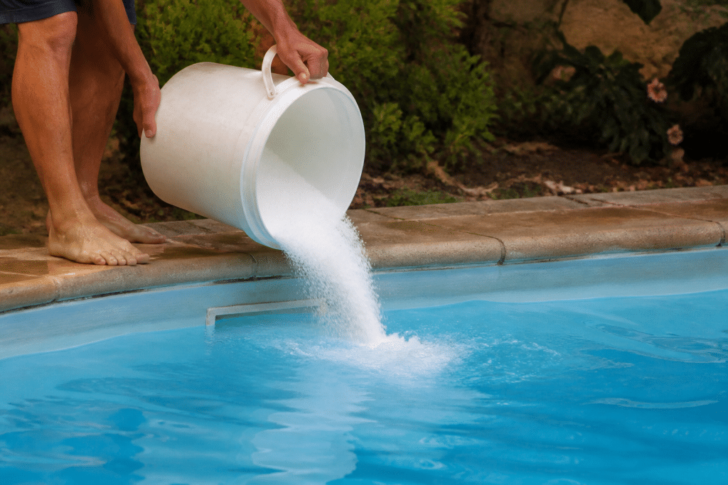 Seau blanc versant poudre blanche dans piscine bleue