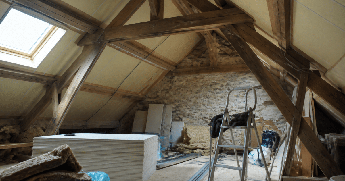 Grenier mansarde avec poutres apparentes et amenagement interieur en cours