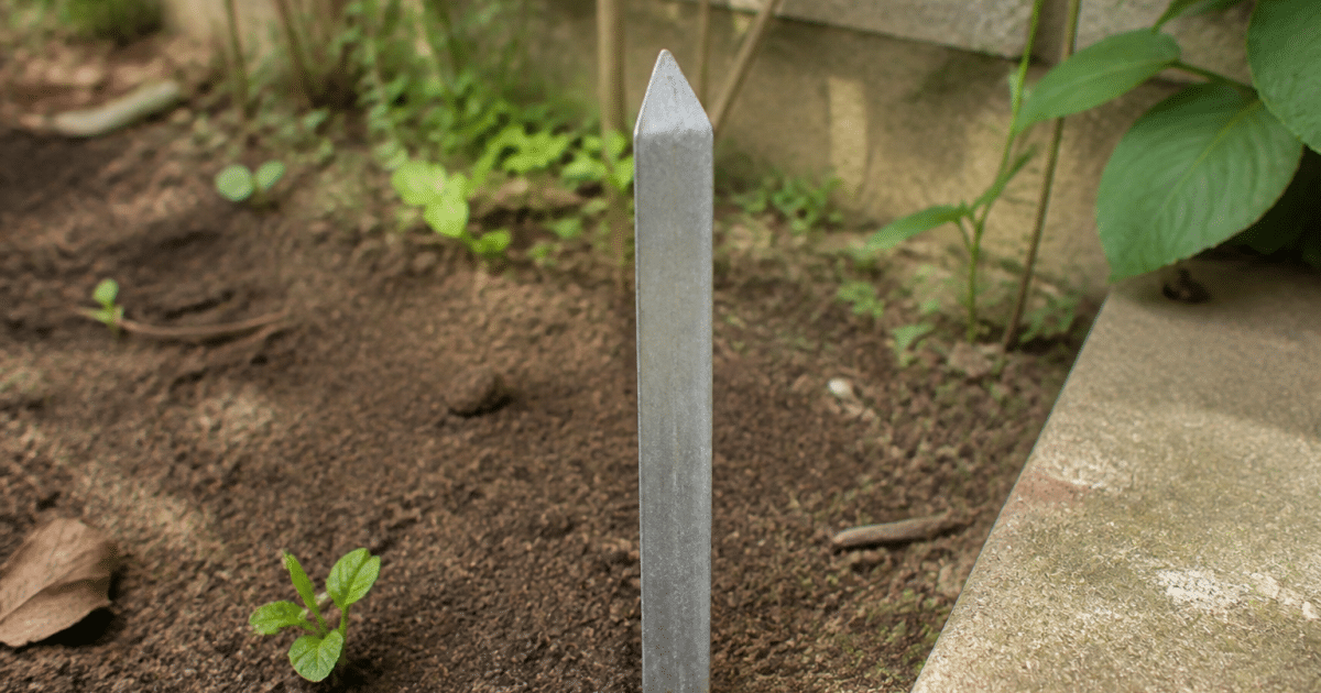 Pic metallique vertical enfonce dans terre de jardin