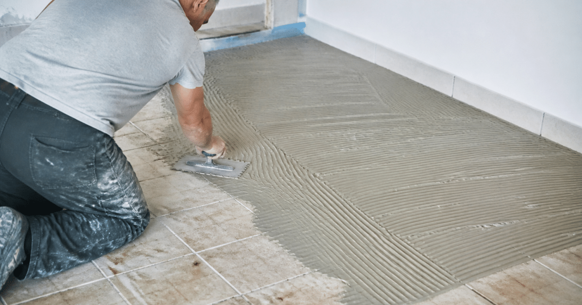 Personne appliquant materiau adhesif sur ancien carrelage sol