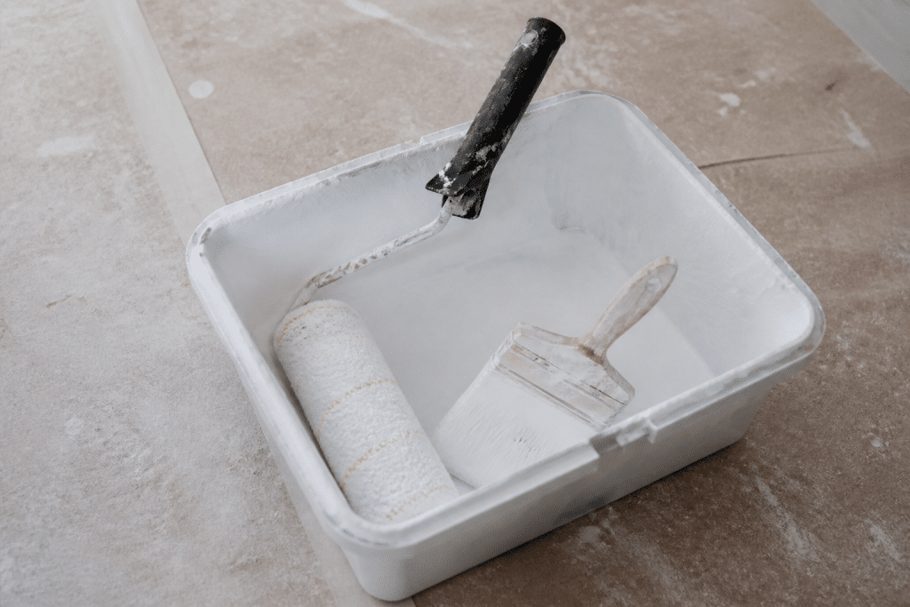 Rouleau et pinceau dans bac a peinture blanc