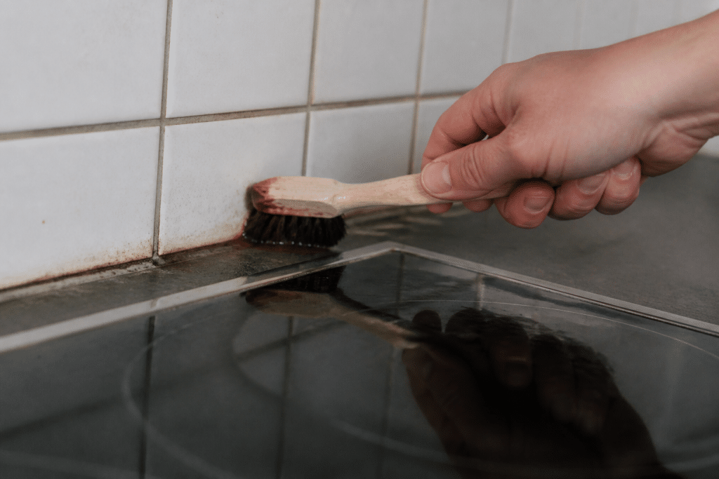 Brosse appliquant savon noir liquide sur joint cuisine encrassé
